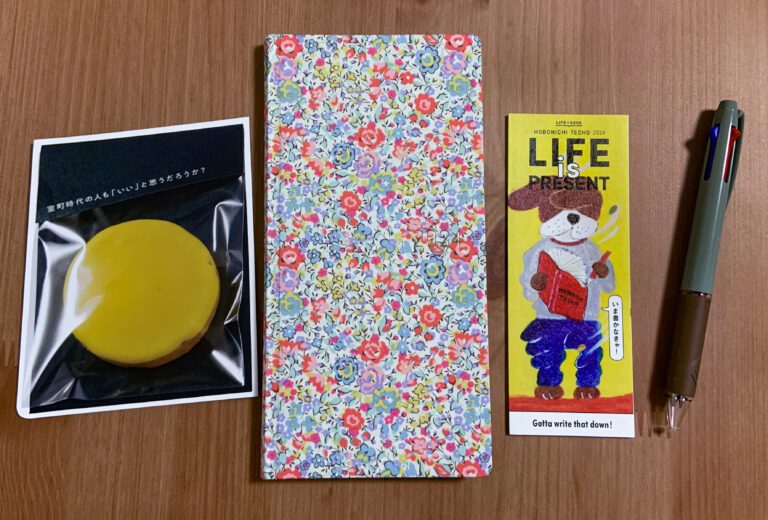 Image of the hobonichi flanked by the card it came with, a manual, and the uni jetstream pen