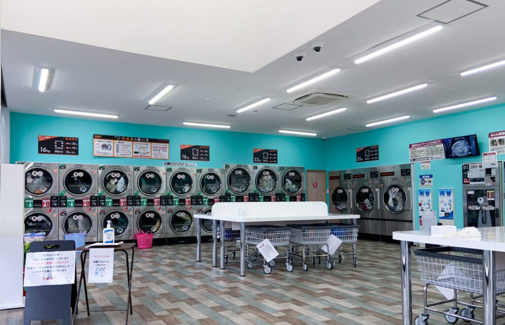 Laundromat with teal walls and large tables