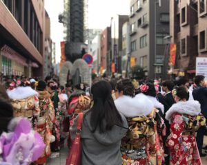 a crowd of women in elaborate kimonos and furs waits to enter the asakusa center